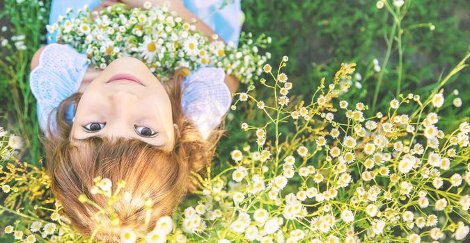 Child girl in a camomile field. Selective focus. nature.