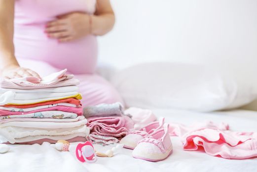A pregnant woman is folding baby things. Selective focus. people.
