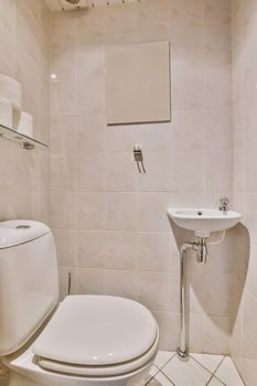 Flush toilet located between sink and shower in small tiled bathroom of contemporary apartment