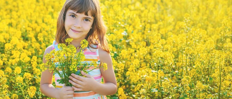 A child in a yellow field, mustard blooms. Selective focus.