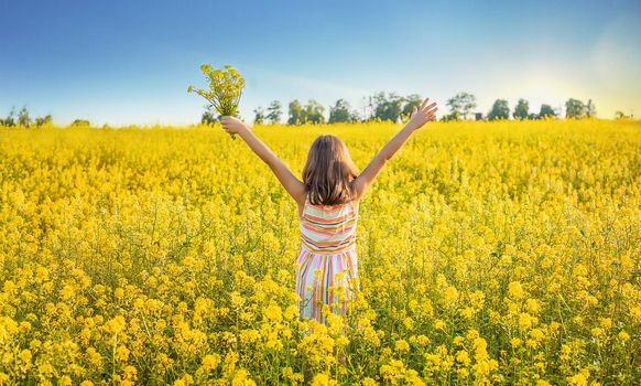 A child in a yellow field, mustard blooms. Selective focus. nature.