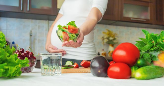 A pregnant woman eats vegetables and fruits. Selective focus. Food.