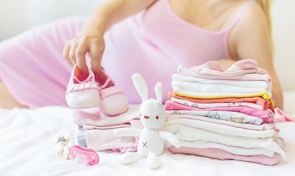 A pregnant woman is folding baby things. Selective focus. people.
