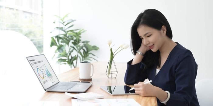 Beautiful young asian woman sitting at coffee shop using laptop. Happy young businesswoman sitting at table in cafe with tab top computer..