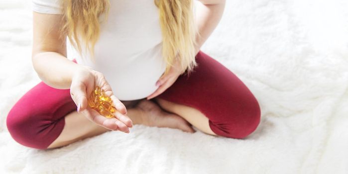 A pregnant woman drinks omega three vitamins. Selective Focus. people.