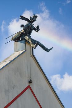 Monument to the chimney sweep in Klaipeda, Lithuania. Blue sky with white clouds and rainbow. Vertical photo.
