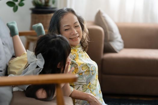 Happy moments of Asian grandmother with her granddaughter talking together in living room at home