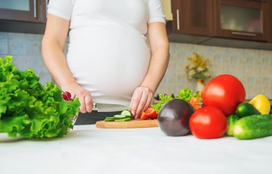 A pregnant woman eats vegetables and fruits. Selective focus. Food.