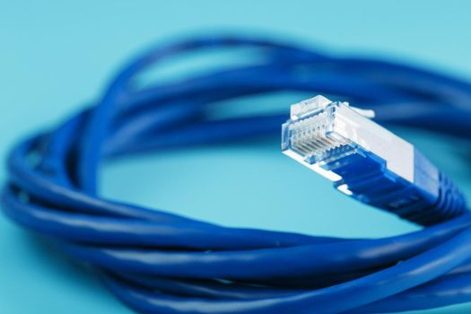 A coil of RJ45 Cat.6 Ethernet Network Internet Cable isolated on a blue background with free space