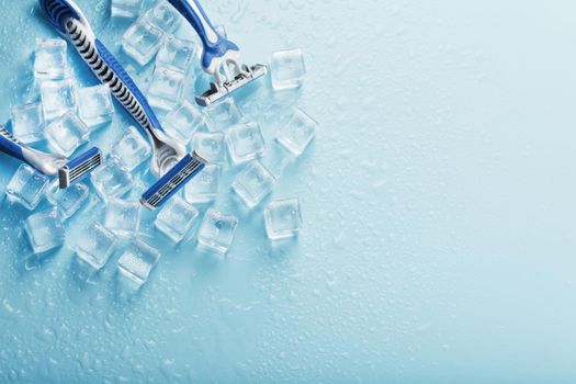 Shaving machine on a blue background with ice cubes. The concept of cleanliness and frosty freshness