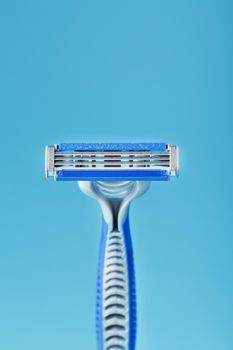 Three shaving machines on a blue background with free space, top view