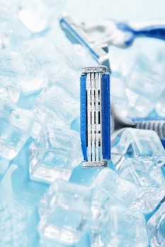 Shaving machine on a blue background with ice cubes. The concept of cleanliness and frosty freshness