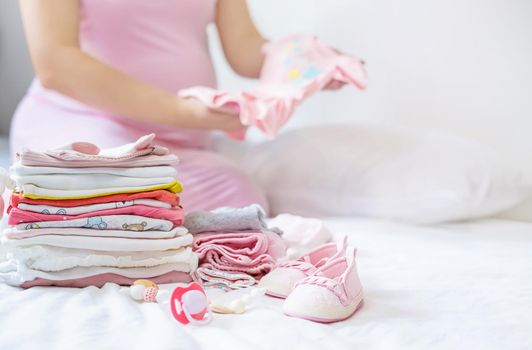 A pregnant woman is folding baby things. Selective focus. people.