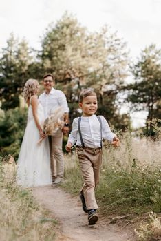 happy family three dad mom and son on a walk in the woods