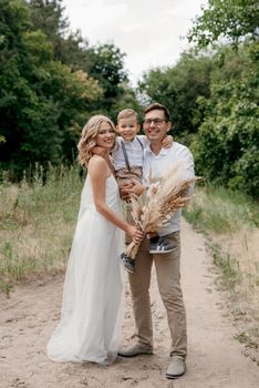 happy family three dad mom and son on a walk in the woods