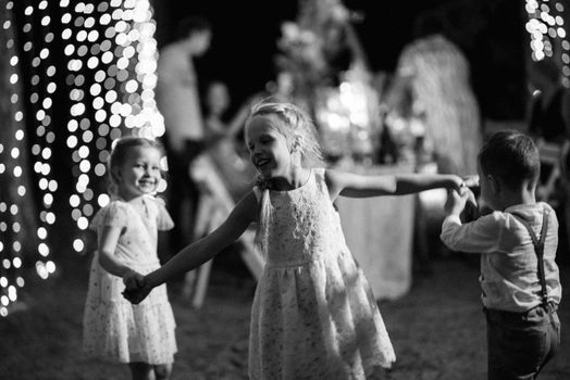 happy children play in a summer pine forest against the background of lights