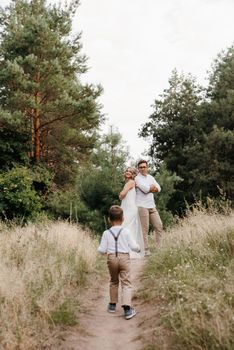 happy family three dad mom and son on a walk in the woods