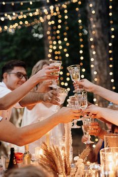 evening wedding family dinner in the forest with light bulbs and candles