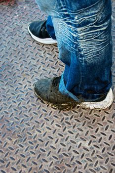 Photo of a dirty pair of tennis shoes and the bottom of a blue jean