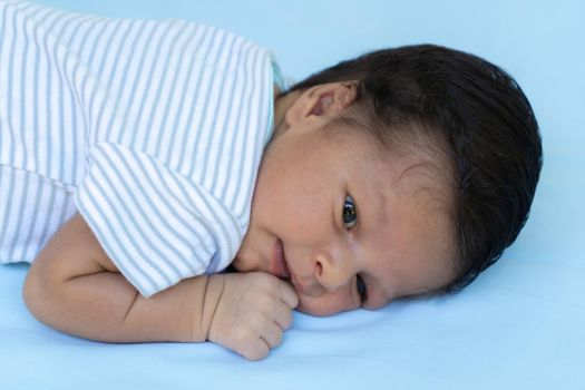 Newborn lying on his stomach, with his eyes open