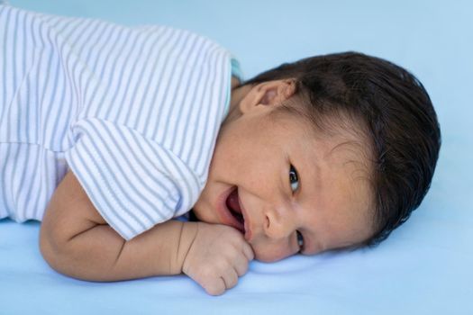 Newborn child lying on his stomach, with a smile expression on his face