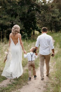 happy family three dad mom and son on a walk in the woods