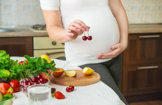 A pregnant woman eats vegetables and fruits. Selective focus. Food.