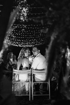 evening wedding family dinner in the forest with light bulbs and candles