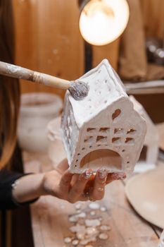 A master ceramist holds a clay product in his hands. Making a ceramic candle holder from clay. The process of coating the candlestick with glaze. Close-up.