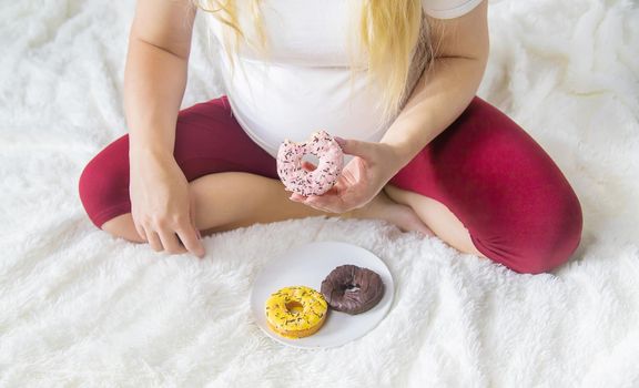 A pregnant woman eats sweet donuts. Selective Focus. Food.