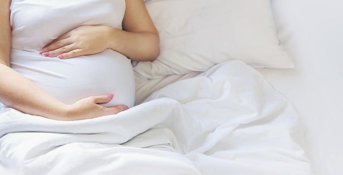 A pregnant woman hugs her belly. Selective focus. People.