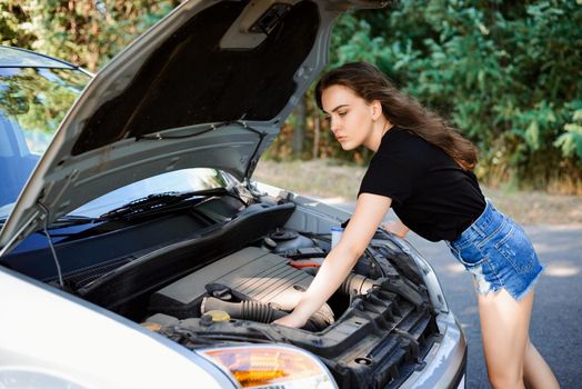 Woman driver checks car engine and tries to repair car by herself