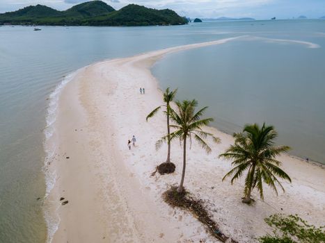 couple of men and women walking on the beach at the Island Koh Yao Yai Thailand, beach with white sand and palm trees.
