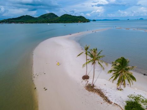 couple of men and women walking on the beach at the Island Koh Yao Yai Thailand, beach with white sand and palm trees.