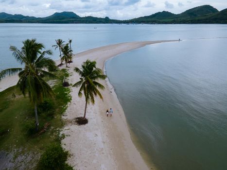 couple of men and women walking on the beach at the Island Koh Yao Yai Thailand, beach with white sand and palm trees.