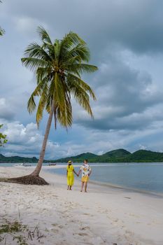 couple of men and women walking on the beach at the Island Koh Yao Yai Thailand, beach with white sand and palm trees.
