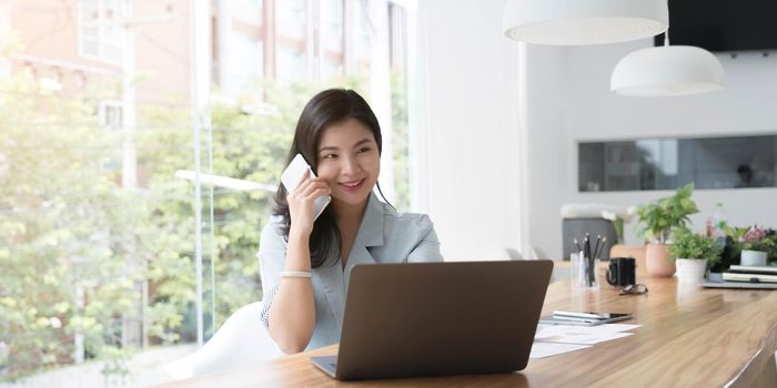 Asian business woman have the joy of talking on the phone, laptop and tablet on the office desk..