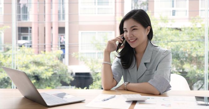 Asian business woman have the joy of talking on the phone, laptop and tablet on the office desk..
