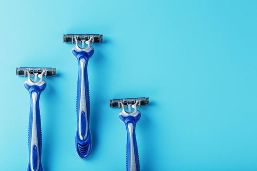 Three shaving machines on a blue background with free space, top view