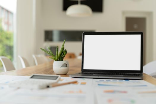 modern laptop computer with blank screen at workplace in office. finance report and calculator accounting on wooden table.