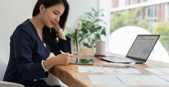 Close up hand of businesswoman using stylus pen signing contract on digital tablet on office table. Business manager proofing e-document, electronic signature, e-signing mobile app.