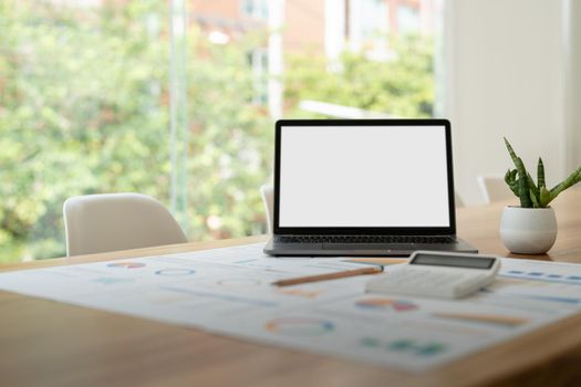 modern laptop computer with blank screen at workplace in office. finance report and calculator accounting on wooden table.