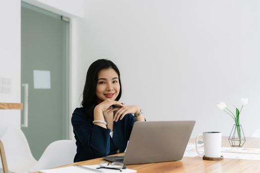 Portrait of happy Asian businesswoman using laptop computer to calculate the numbers, finance accounting concept.