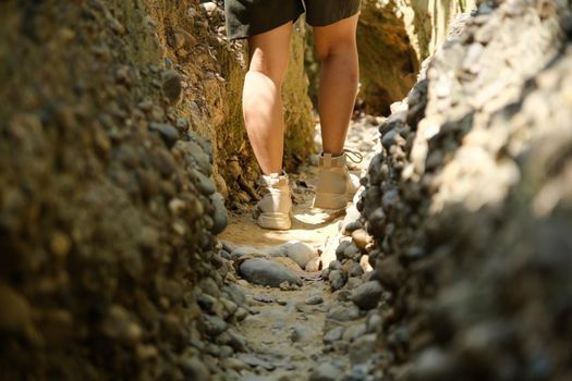 Close-up of the legs of young woman in hiking boots with a backpack walking and enjoying nature in the tropical forest. Travel and Lifestyle Concepts
