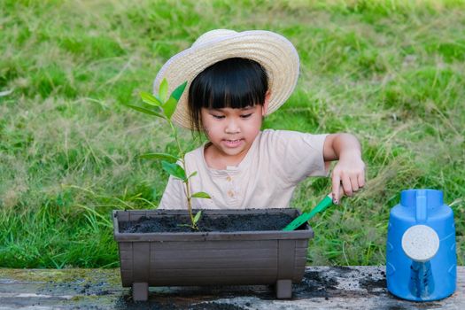 Little girl wearing a hat helps her mother in the garden, a little gardener. Cute girl planting flowers in pots for sale. family small business