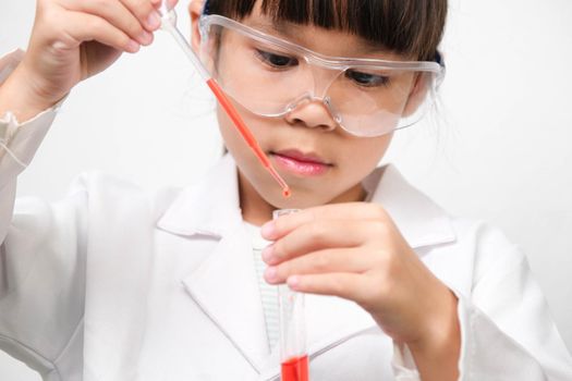 Little scientist. Smiling little girl learning classroom in school lab holding test tubes. Little girl playing science experiment for home schooling.