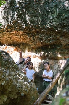 Happy family of Asian tourists looking through binoculars to see wild birds in the forest. Explorer family use binoculars to travel and have a happy smile. Travel and Lifestyle Concepts