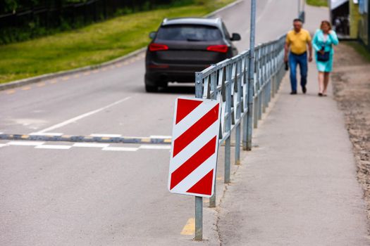 warning red and white diagonal striped vertical marking 8.22.2 sign at the end of road fence, separating road and