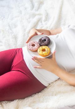 A pregnant woman eats sweet donuts. Selective Focus. Food.