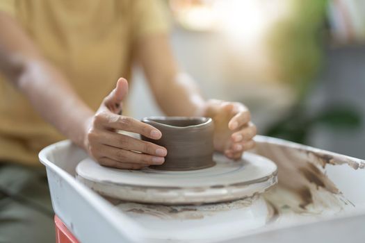 Craftsman hands making pottery bowl. Woman working on potter wheel. Family business shop sculpts pot from clay